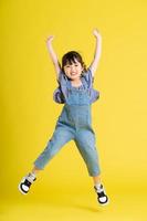 full body image of beautiful asian baby girl on yellow background photo