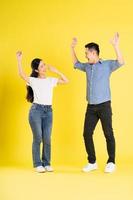 full body image of asian couple posing on yellow background photo