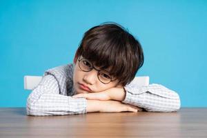 retrato de colegio chico sentado y estudiando en un azul antecedentes foto