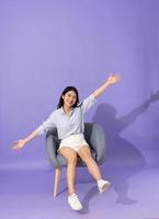image of girl sitting on sofa  isolated on purple background photo