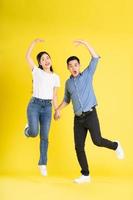 full body image of asian couple posing on yellow background photo