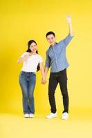 full body image of asian couple posing on yellow background photo