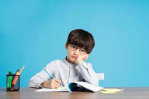 portrait of school boy sitting and studying on a blue background photo