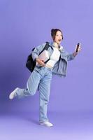 Portrait of a beautiful Asian schoolgirl wearing a backpack on a purple background photo