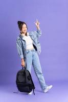 retrato de un hermosa asiático Chica de escuela vistiendo un mochila en un púrpura antecedentes foto