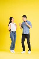 full body image of asian couple posing on yellow background photo