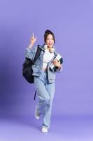 retrato de un hermosa asiático Chica de escuela vistiendo un mochila en un púrpura antecedentes foto