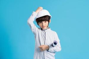 Asian boy portrait playing the role of an engineer, isolated on blue background photo