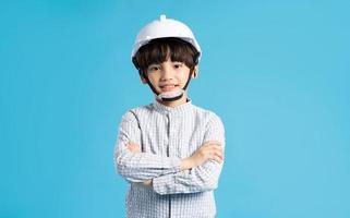 Asian boy portrait playing the role of an engineer, isolated on blue background photo