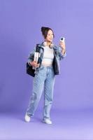 Portrait of a beautiful Asian schoolgirl wearing a backpack on a purple background photo