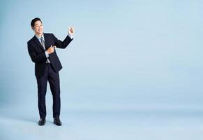 portrait of asian businessman wearing suit on blue background photo