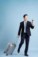 Portrait of Asian businessman wearing a suit and pulling a suitcase photo