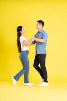 full body image of asian couple posing on yellow background photo