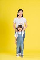 image of asian mother and daughter posing on a yellow background photo