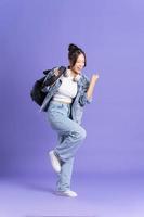 Portrait of a beautiful Asian schoolgirl wearing a backpack on a purple background photo