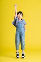 full body image of beautiful asian baby girl on yellow background photo