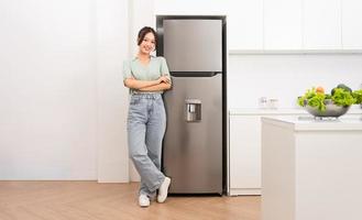 Asian woman standing next to the refrigerator in the kitchen photo