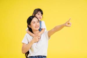 image of asian mother and daughter posing on a yellow background photo