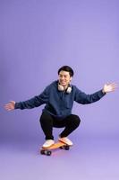 Image of young Asian man playing skateboard on purple background photo