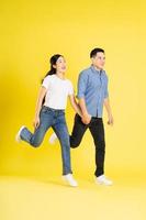full body image of asian couple posing on yellow background photo