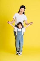 image of asian mother and daughter posing on a yellow background photo