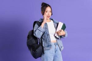 retrato de un hermosa asiático Chica de escuela vistiendo un mochila en un púrpura antecedentes foto