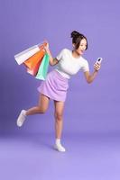 Young Asian woman holding shopping bag on purple background photo