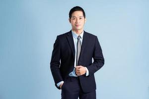 portrait of asian businessman wearing suit on blue background photo