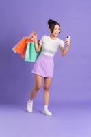 Young Asian woman holding shopping bag on purple background photo