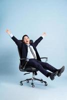 Asian businessman male portrait sitting on chair and isolated on blue background photo