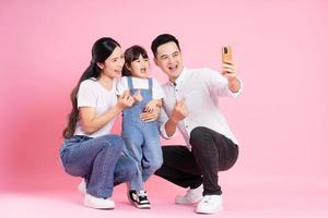 happy young asian family image, isolated on pink background photo