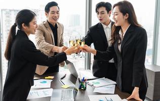 group of Asian business people holding glasses of wine to celebrate new year photo