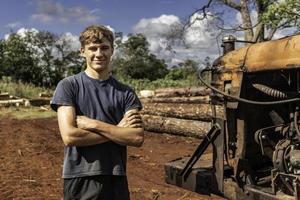 Young boy working in a sawmill smiling and looking at the camera photo