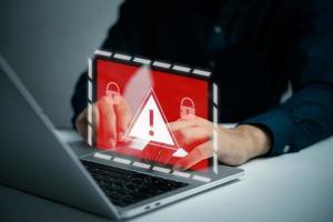 Businessman programmer, developer using laptop computer with triangle caution warning sign. system hacked on computer network cybersecurity vulnerability. photo