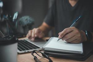 man hands with pen writing on notebook in the office.learning, education and work.writes goals, plans, make to do and wish list on desk. photo