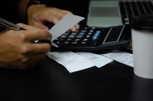 Man hand holding bill and pen with calculator expense or tax receipt. business finance concept. photo