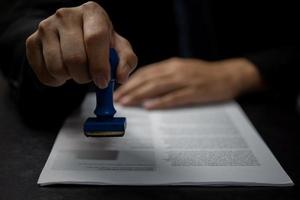 Man stamping approval of work finance banking or investment marketing documents on desk. photo