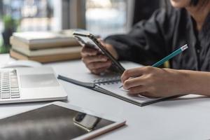 mujer manos con bolígrafo escritura en cuaderno en el oficina.aprendizaje, educación y trabajo.escribe objetivos, planes, hacer a hacer y deseo lista en escritorio. foto