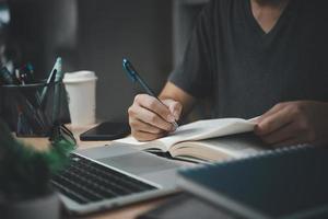 man hands with pen writing on notebook in the office.learning, education and work.writes goals, plans, make to do and wish list on desk. photo