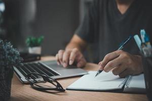 man hands with pen writing on notebook in the office.learning, education and work.writes goals, plans, make to do and wish list on desk. photo