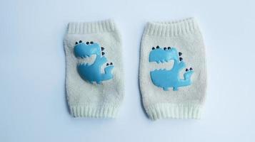 Cute blue monster beige baby knee pad sock isolated on white, knee protection for baby learn to crawl. photo