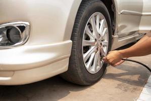 Asian man inflating tires at gas station And he's looking at the dial of the auto-inflator to check the pressure level, inflate the tires. photo