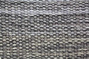 Woven grey wool fabric texture. Hand knitted textile canvas background. Patchwork carpet backdrop. Factory material threads. Abstract design. Close-up, mockup, top view photo