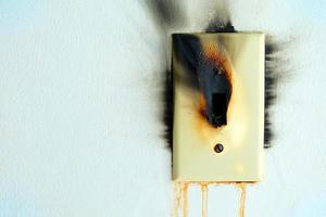 Burned Electrical Switch with White Concrete Wall Texture Background. photo