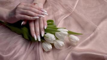 hermosa manos de un joven mujer con blanco manicura en clavos. video