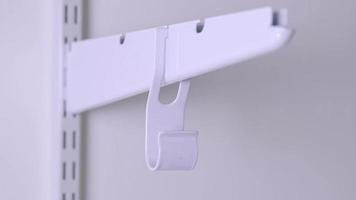 Installation brackets of a metal mesh shelf in the dressing room system on a bracket. Hands is assembling a white holder storage system close-up video