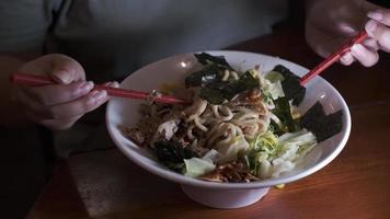 Stirring soup-less ramen using red chopsticks in a white bowl video