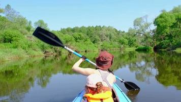 família caiaque viagem. mãe e filha remo uma barco em a rio, uma água caminhada, uma verão aventura. ecológico e extremo turismo, ativo e saudável estilo de vida video