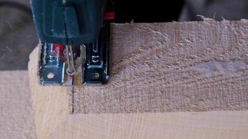 Sawing a board with an electric jigsaw in close-up. Carpentry on wood with a tool, sawdust flies, the saw cuts in a straight line. Home repair with your own hands, a sawmill. Slow motion video