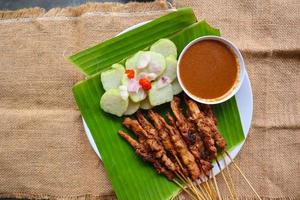 pollo satay o pollo satay servido con mucho tiempo, arroz pastel y maní salsa. servido en plátano salir foto